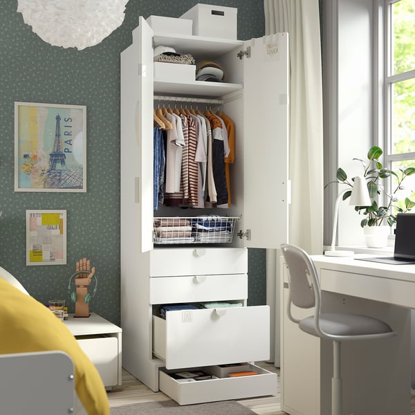 White childrens wardrobe with clothes and drawers in a green bedroom.