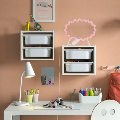 Kids desk with SNÖDJUP lamp, toys, and drawing on wall.
