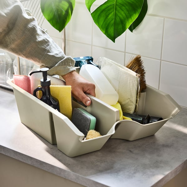 Person accessing cleaning supplies in a SORTERA storage bin on a countertop.
