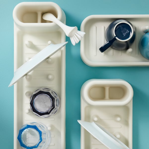 White dish drainer holding various dishware; includes knives and mugs, stacking design for space-saving.