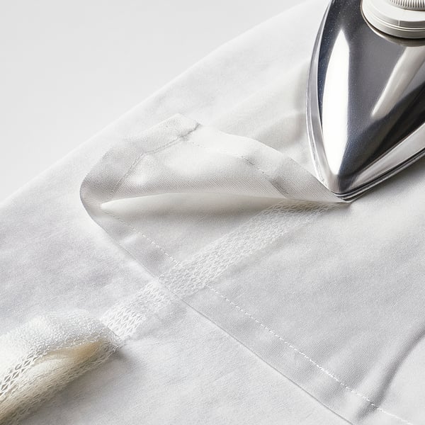 A shiny iron presses a sheer white curtain, creating crisp folds. The curtains soften sunlight and add fullness to windows.