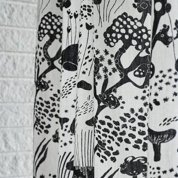 B&w curtain with patterns on textured wall.
