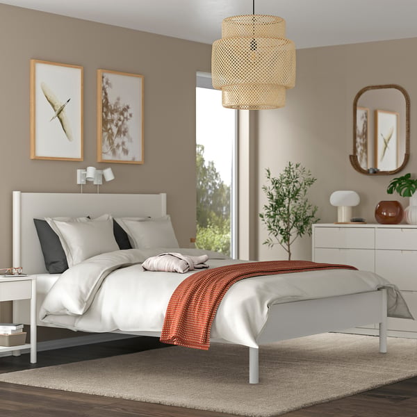 Modern bedroom with STOENSE rug, white bed, butterfly wall art, pendant light, dresser with plant and pottery.