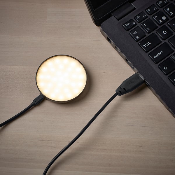 A modern desk setup with a laptop and a connected usb-powered round spotlight. The spotlight illuminates the workspace efficiently.