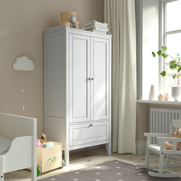 White SUNDVIK wardrobe with 2 doors & drawers between window & crib.