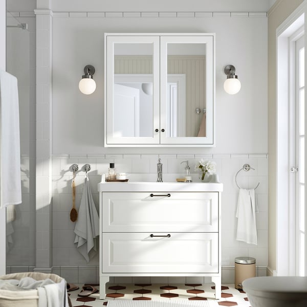 Modern white bathroom with TÄNNFORSEN vanity, mirror cabinet, chrome fixtures, grey towels, and patterned floor.