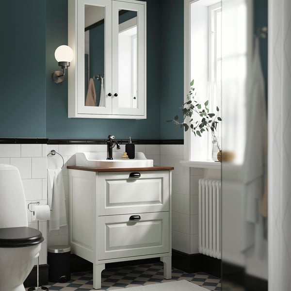 IKEA TÄNNFORSEN white vanity with basin, mirror cabinet, and drawers beneath, against teal wall.