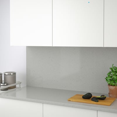 A modern kitchen with a TÄRNHULT recycled glass backsplash, featuring a cutting board with avocados and a potted plant.