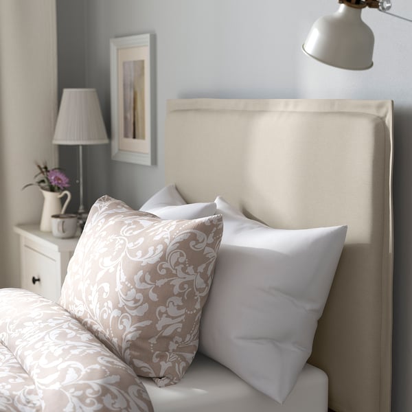 Cosy bed with soft, removable cover, decorative pillows, and padded headboard for comfort.