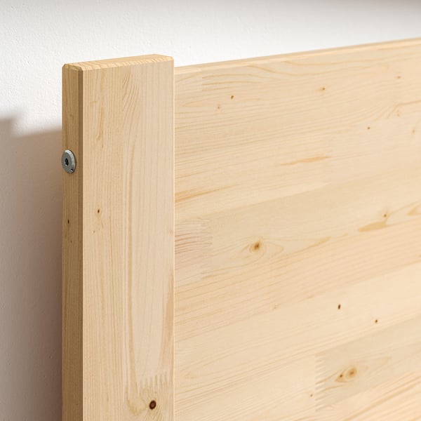Close-up of taxasklint bed frames corner in natural pine wood showing solid construction.