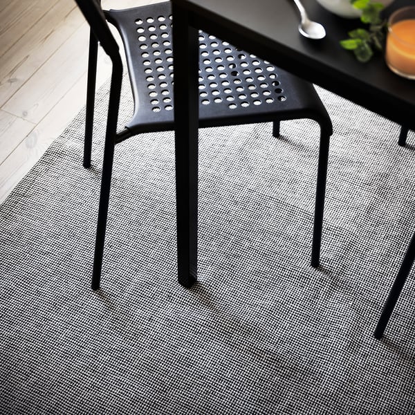 Black modern chair on a grey rug with subtle pattern.