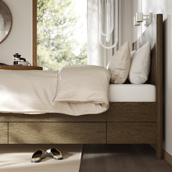 Bedroom scene with a TONSTAD bed, showcasing its classic design and under-bed storage drawers, ideal for extra linens and clothes.