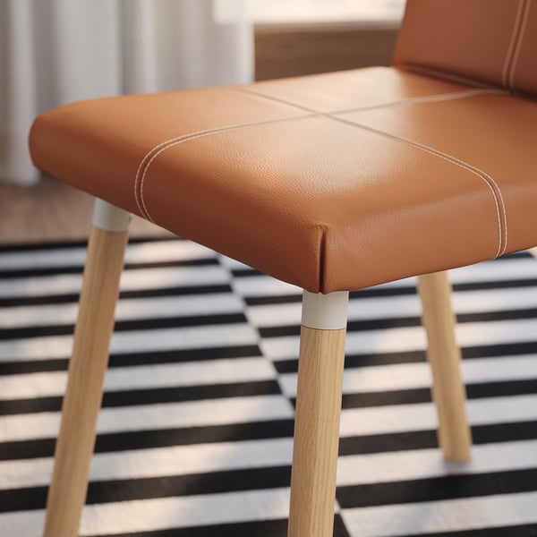 Close-up of TONSTAD chairs upholstered seat, showcasing detailed stitching and wooden legs.