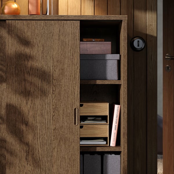 Wardrobe with open shelving displaying boxes and books, beside a closed wooden door. Shows adjustable shelves for customizable storage.