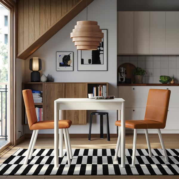 Modern dining with TONSTAD table, orange chairs, wooden pendant, black-and-white rug.