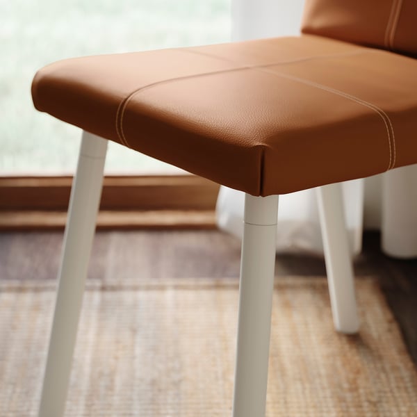Modern chair with cushioned seat and white legs.