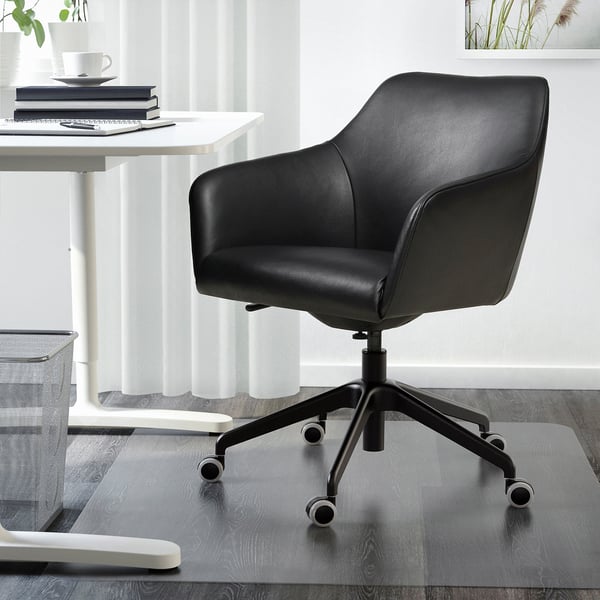 TOSSBERG black leather swivel chair next to white desk.