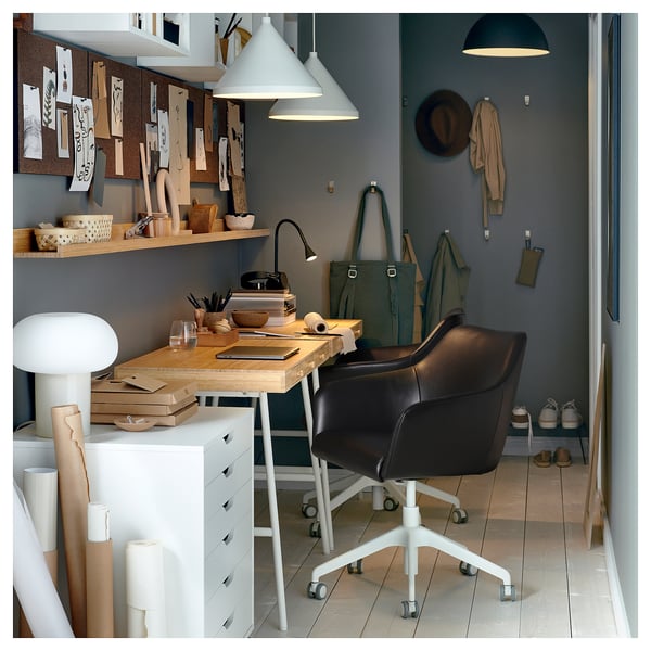 Home office with TOSSBERG black leather swivel chair, wooden desk, hanging lamps, green walls, and organisers.