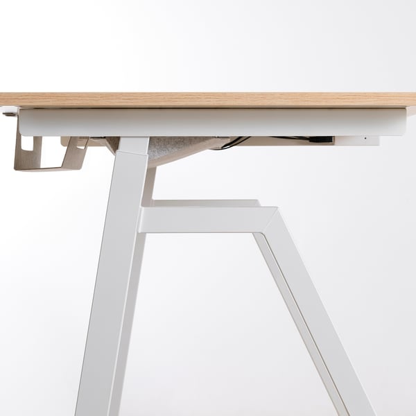 Modern sit/stand desk with white frame, light wood top, and hidden leg design.