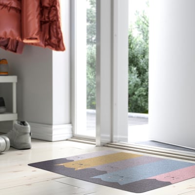 Colourful rectangular TURISTVÄG mat lies near a large window, surrounded by shoes and a small table.