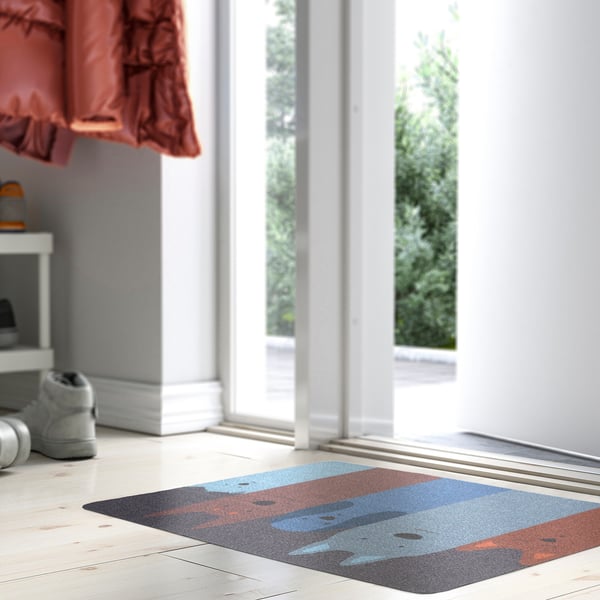 Small colourful mat, star wars design, under door, light floor.