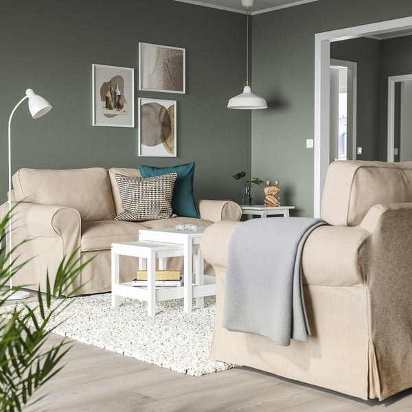 Modern living room with UPPLAND sofas, green walls, and minimalist decor. Beige sofas are cosy with a small white coffee table.