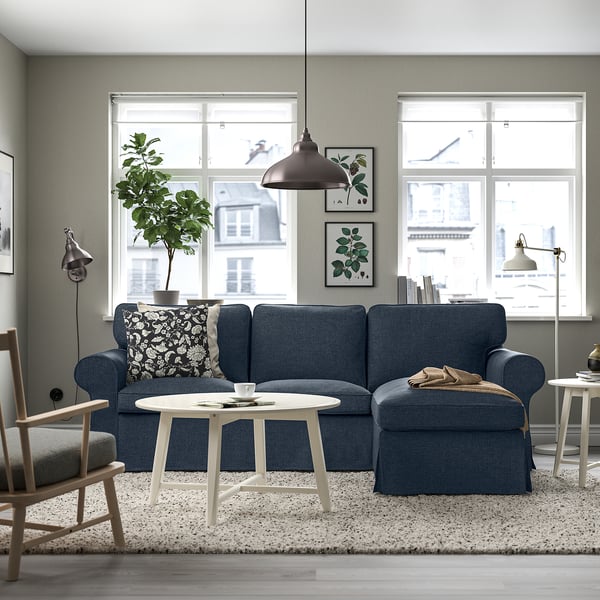 Cosy modern living room with large UPPLAND blue sectional sofa, white coffee table, and large windows showing city view.