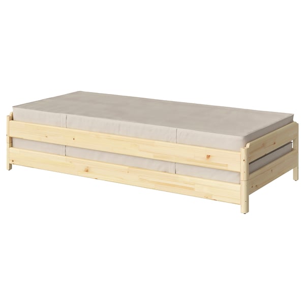 A UTÅKER pine wood single bed with a beige mattress. Its simple, stackable, and ideal for space-saving.