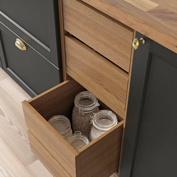 Wooden kitchen drawer open, revealing glass jars with grains. Part of VADHOLMA storage solution, featuring smooth, self-closing mechanism.