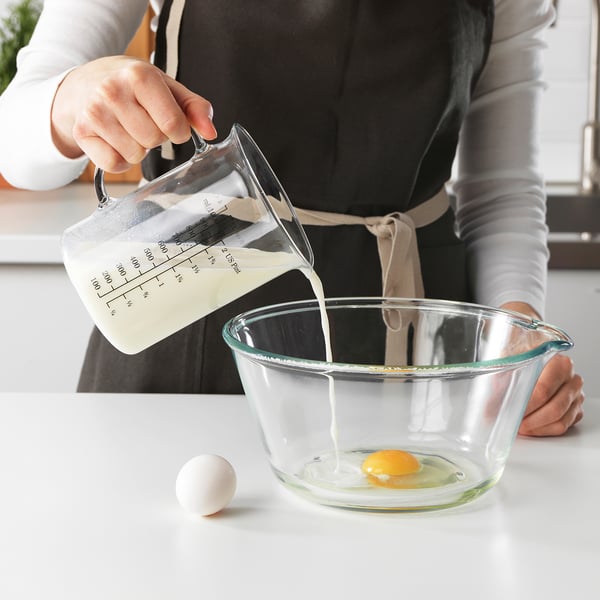 Pouring liquid from jug into bowl with egg.