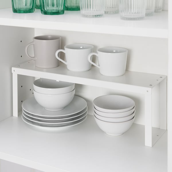 White shelf organiser stacks cups, bowls, and plates in cabinet for efficient storage.