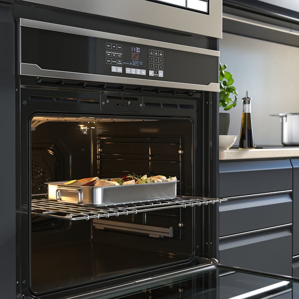 Modern kitchen with built-in oven. Its showing self-cleaning, with temperature display and digital controls. Food is inside, ready to bake.