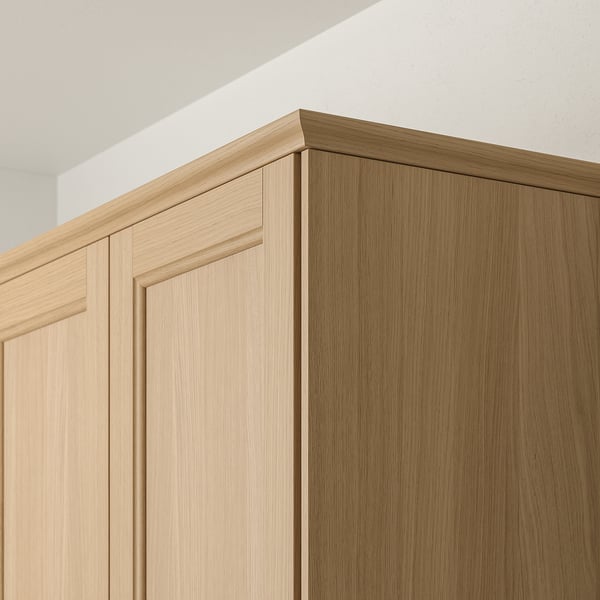 Wooden kitchen cabinet trim in light oak finish, shown near ceiling, part of IKEAs VEDHAMN series.