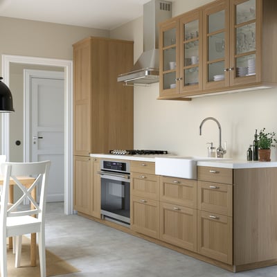 Modern kitchen with oak cabinets, stainless steel appliances, white sink, glass doors, and minimalist design.