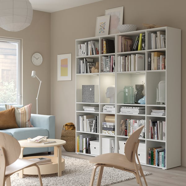 White bookshelf with books, decor, chair, and blue sofa in stylish living room.