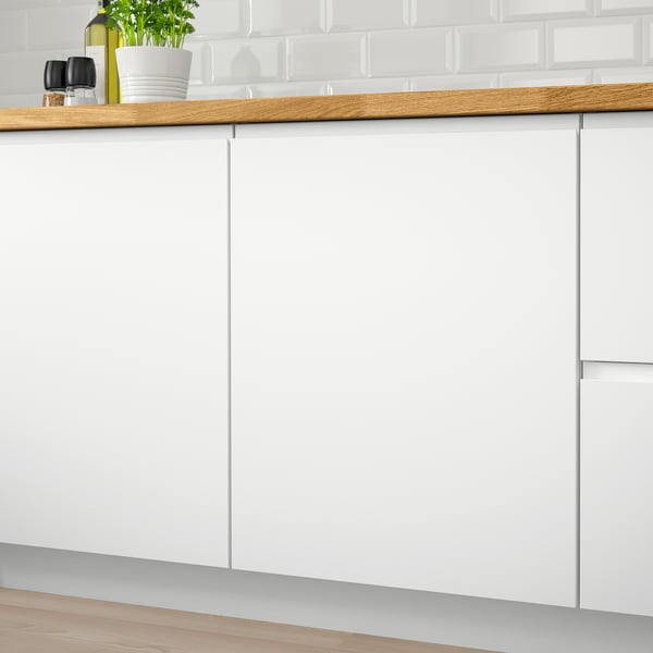 Minimalist white kitchen cabinets with integrated handles, sleek wood countertop, and subtle greenery.