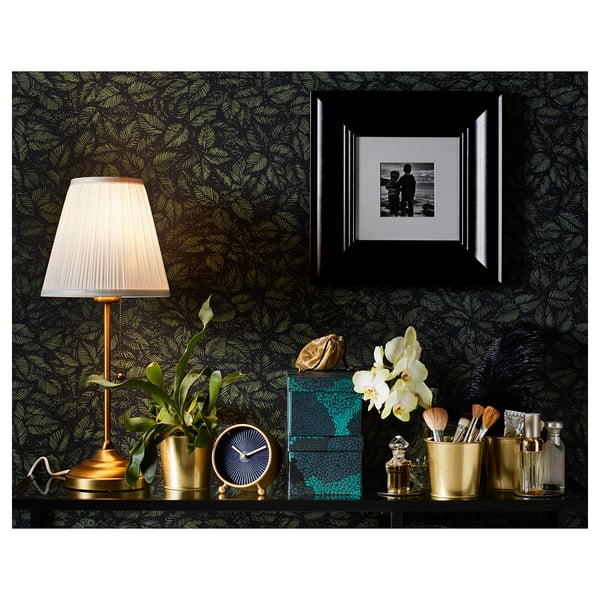 Green wall bedroom decor with gold clock, plant, black photo frame, lamp