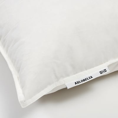Close-up of a soft, white pillow with AXLOBELIA brand tag, high-quality cotton and feather filling, ideal for side or back sleepers.
