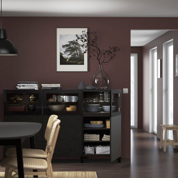 Modern dining area with dark sideboard, dishes, vase, and wicker chairs.
