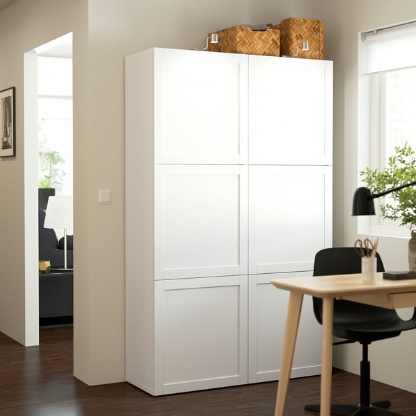 White BESTÅ storage unit in living space, taller than adjacent desk, with woven baskets on top.