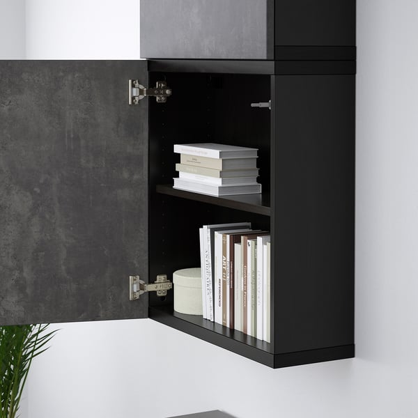 Black wall-mounted cabinet with two shelves holding books, demonstrating organised storage solution.