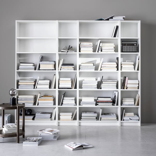 Large white BILLY bookcases with numerous books and minimalist decor. Clean, organised, modern design.