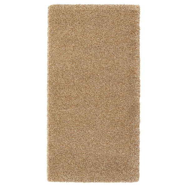 A light brown rectangular rug named BREVBÄRARE made of polypropylene and synthetic rubber for durability and comfort.