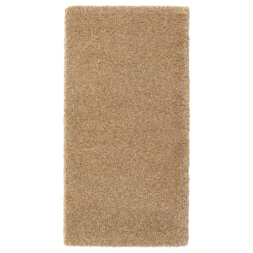 A light brown rectangular rug named BREVBÄRARE made of polypropylene and synthetic rubber for durability and comfort.
