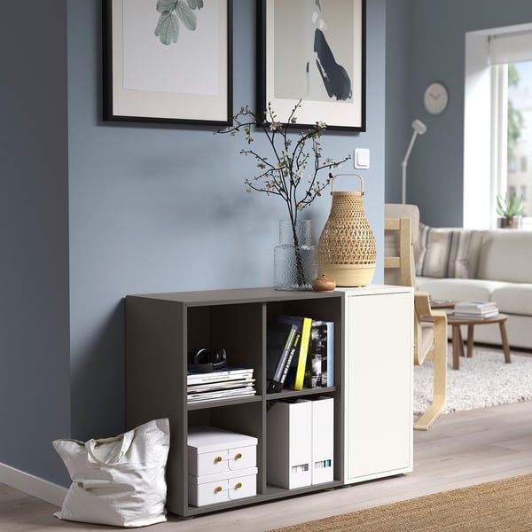 Modern living space with grey EKET storage unit. Drawers, shelves, decor. Blue wall, art, fits under window.