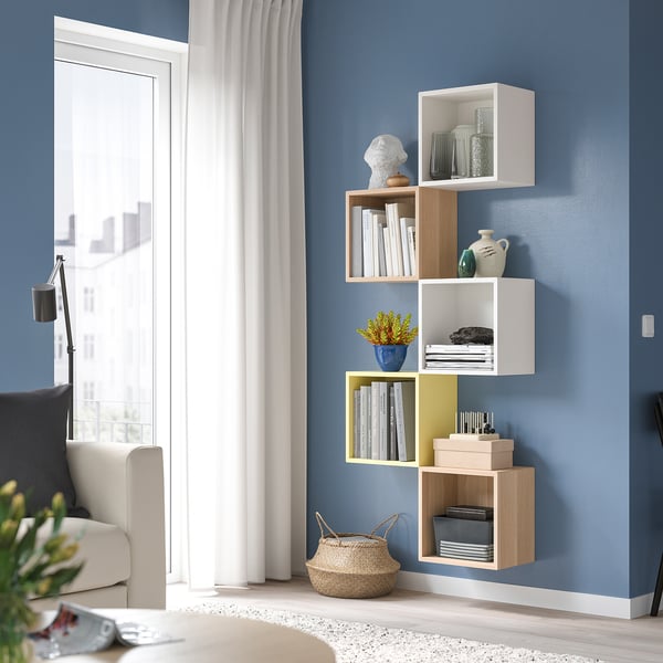 Modern blue room with EKET storage, books, vases, grey chair.