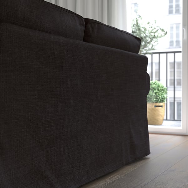 Dark sofa near a window with plants, offering comfort and easy-to-clean covers.