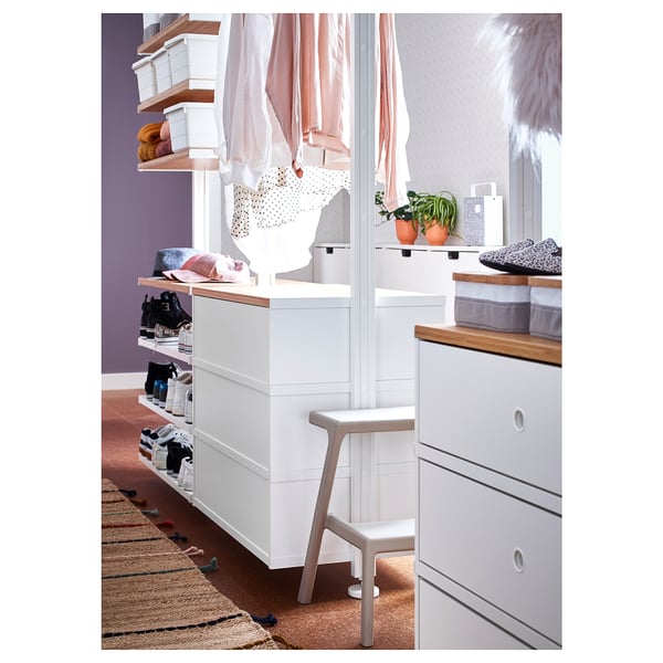 Modern bedroom with white storage, shelves, drawers, hanging rail, purple walls, rug.