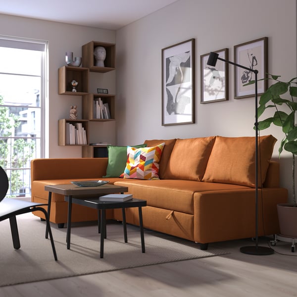 Bright orange FRIHETEN sofa-bed in modern living room. Its large, matching other furnishings, with colourful pillows and art on walls.