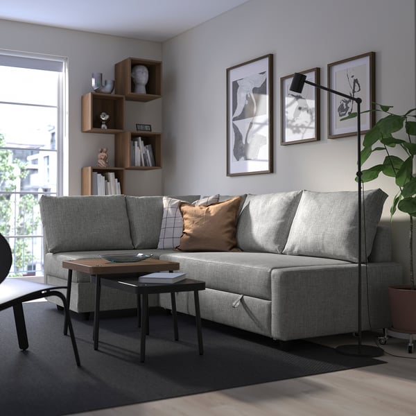 Modern living room with FRIHETEN sofa-bed, art, coffee table, shelves, lamp.